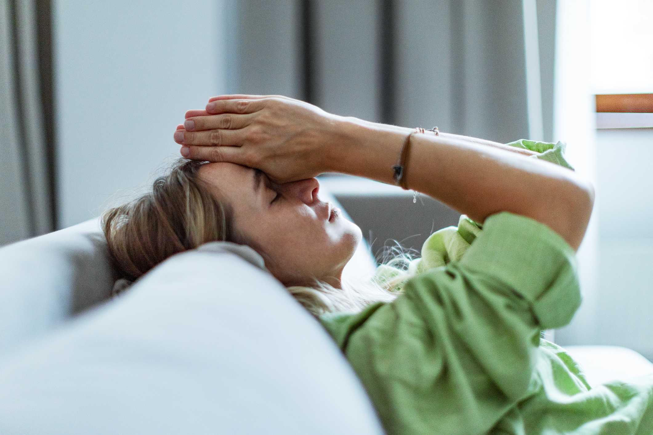 Kvinne sitter alene og ser ned, et bilde på belastningen ved å stå i alvorlig sykdom og samtidig måtte kjempe for å bli trodd.